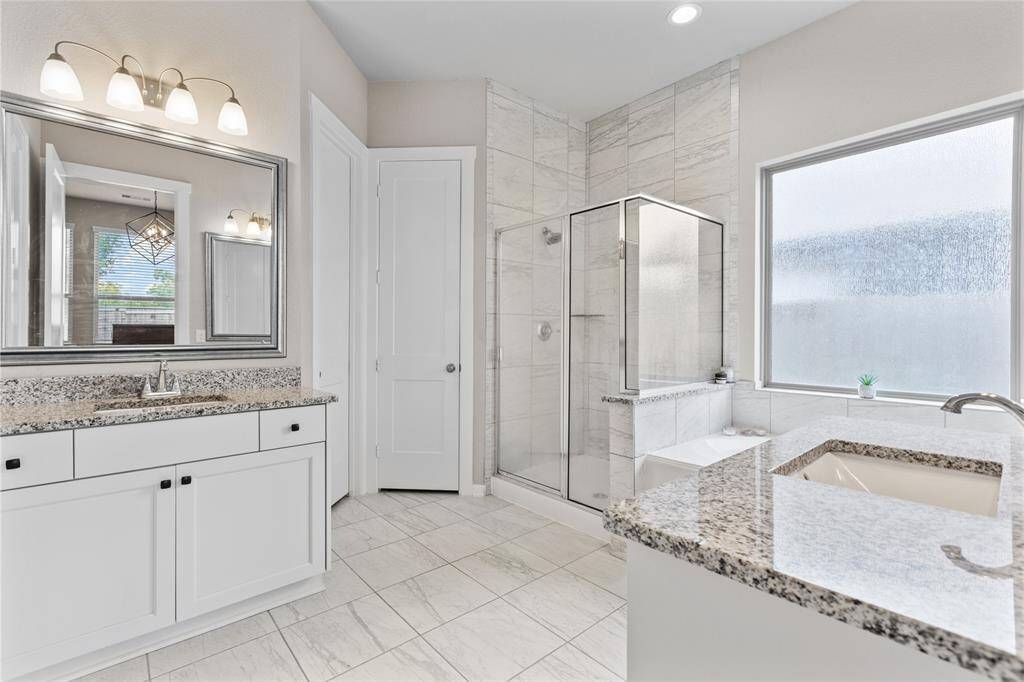 Luxurious primary bath featuring a walk-in shower, soaking tub, and dual vanities.