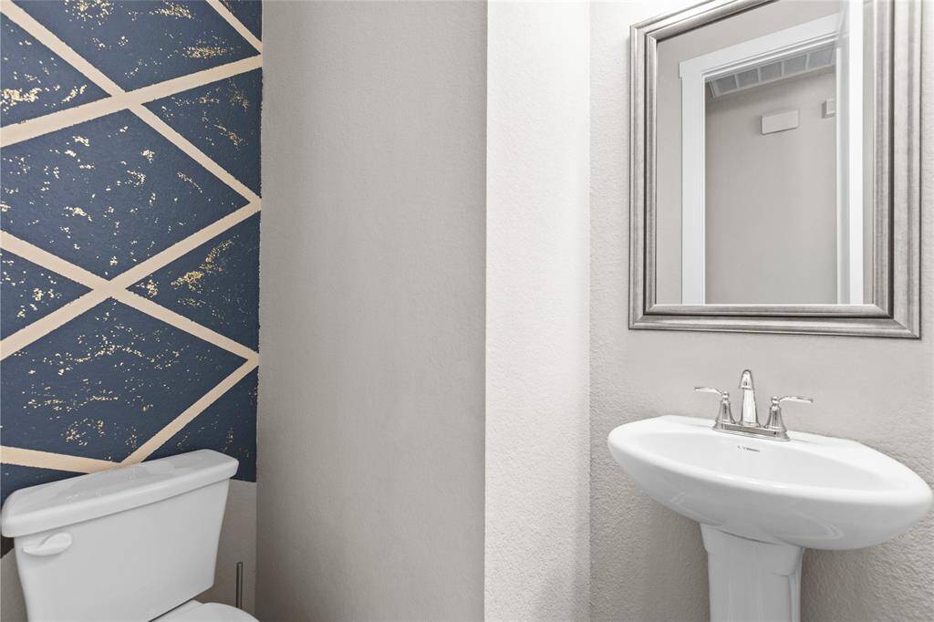 Elegant half bath featuring modern fixtures and stylish accent wall.