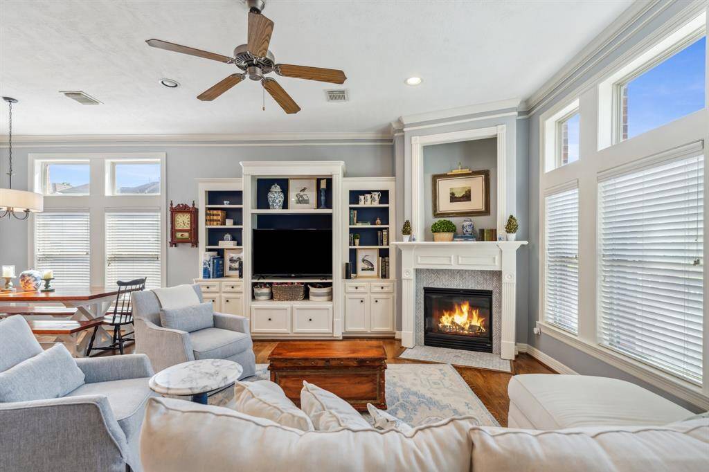 The living area exudes warmth and sophistication, with high ceilings, crown moldings, and a gas fireplace, ideal for cozy evenings.