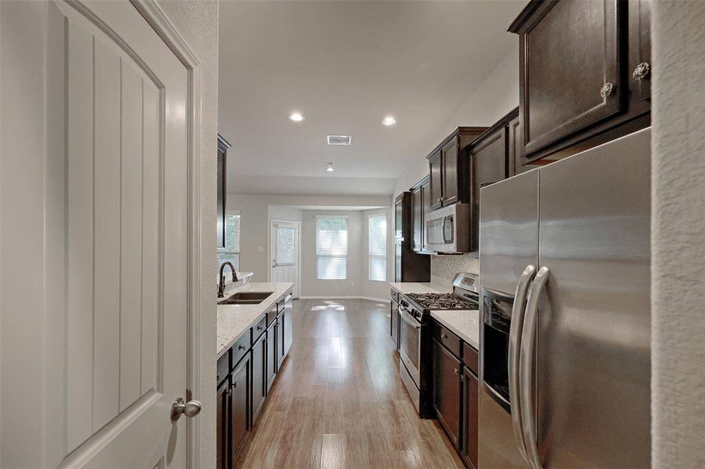Galley style kitchen was recently updated with quartz counters and glass tile backsplash. A pantry to the left provides storage.