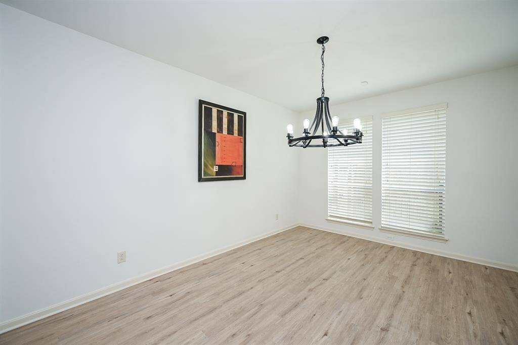 This dining room features a chandelier, new floors, fresh paint, and large windows.