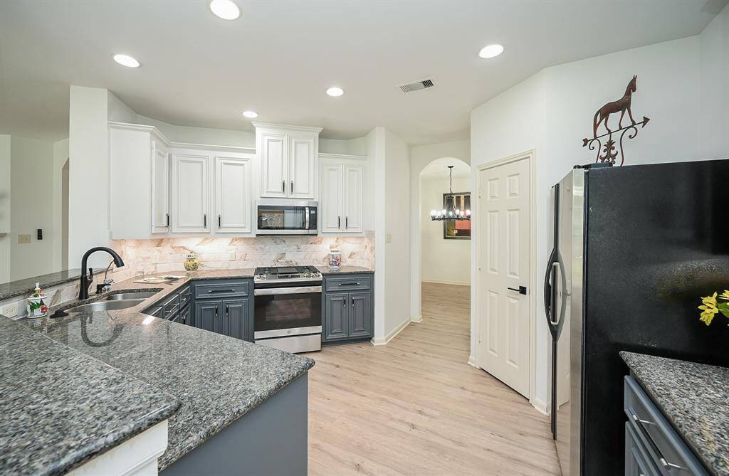 The kitchen features custom cabinets, tile backsplash, and granite countertops creating a clean and timelessaesthetic.