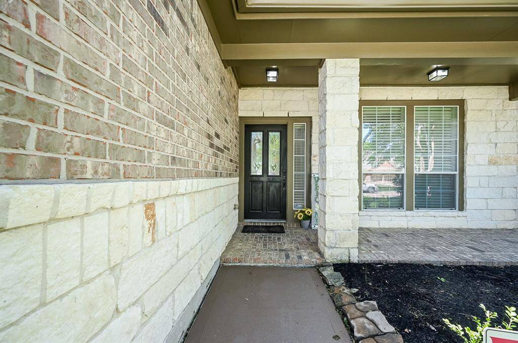 Approaching the front door you will see the brick and stone elevation, covered front porch, and dark stained front door.