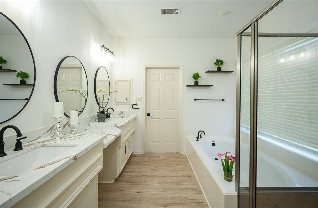 The primary bathroom features dual sinks, vanity area, walk-in shower, and separate tub.