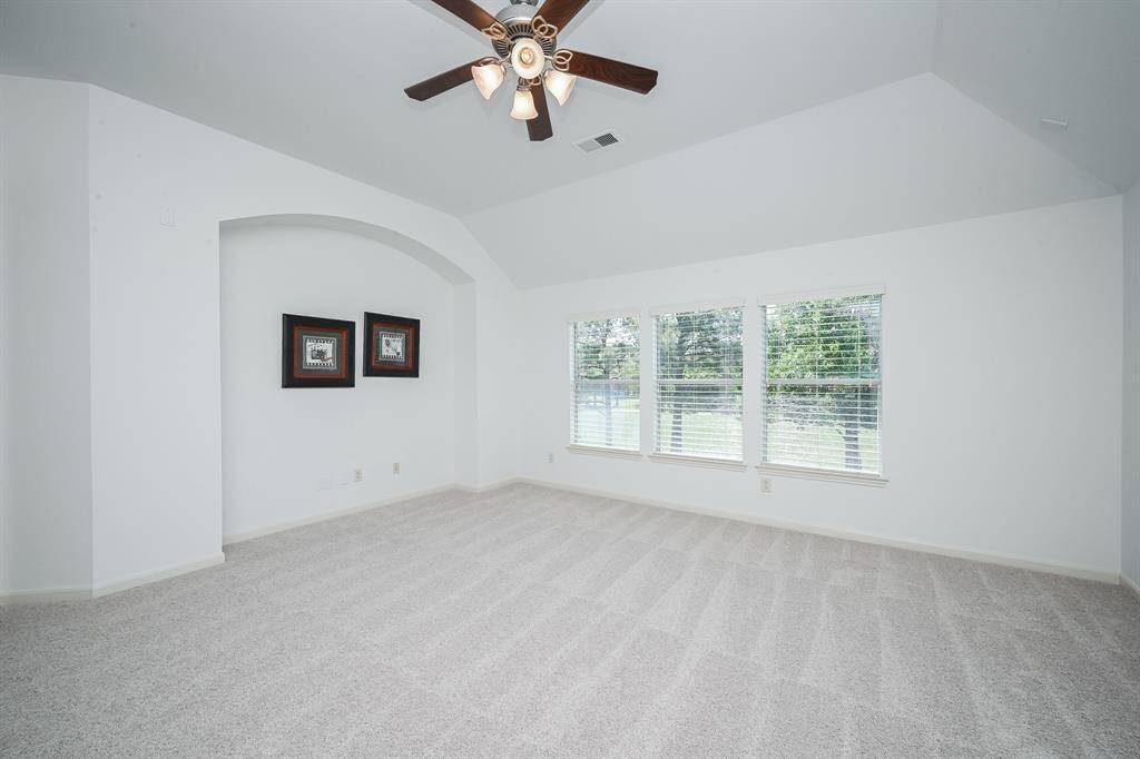 The game room features plush carpet, high ceilings, ceiling fan, and large windows.
