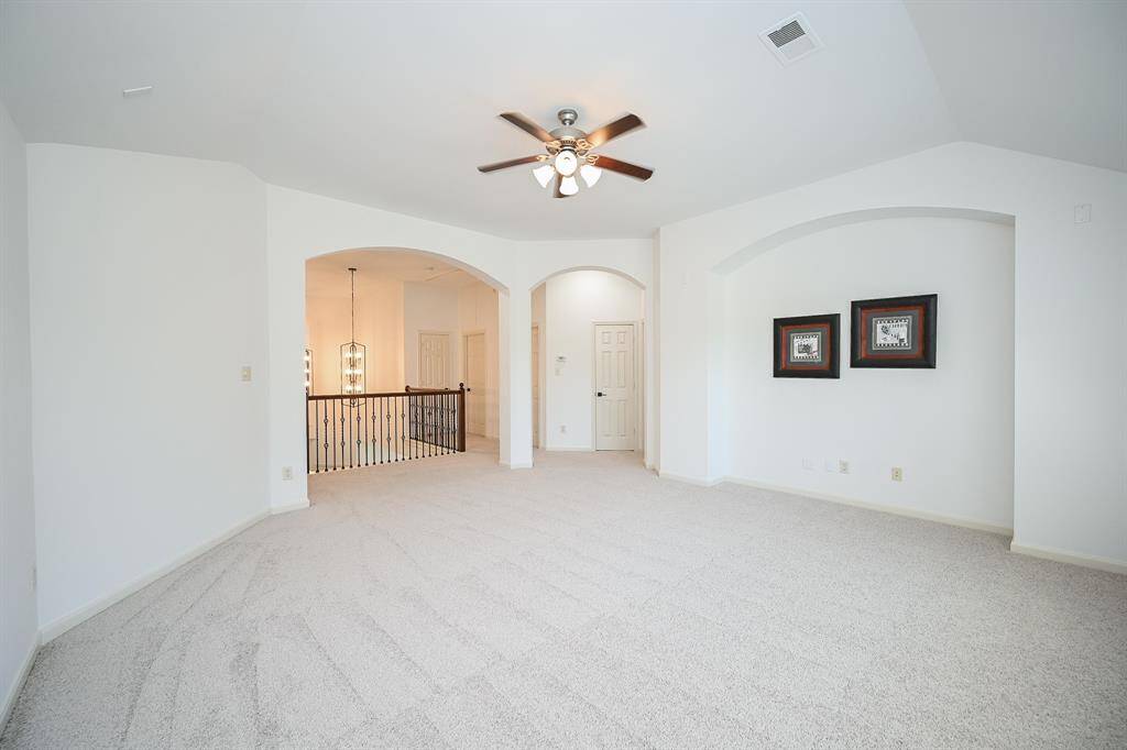 The game room features plush carpet, high ceilings, ceiling fan, and large windows.
