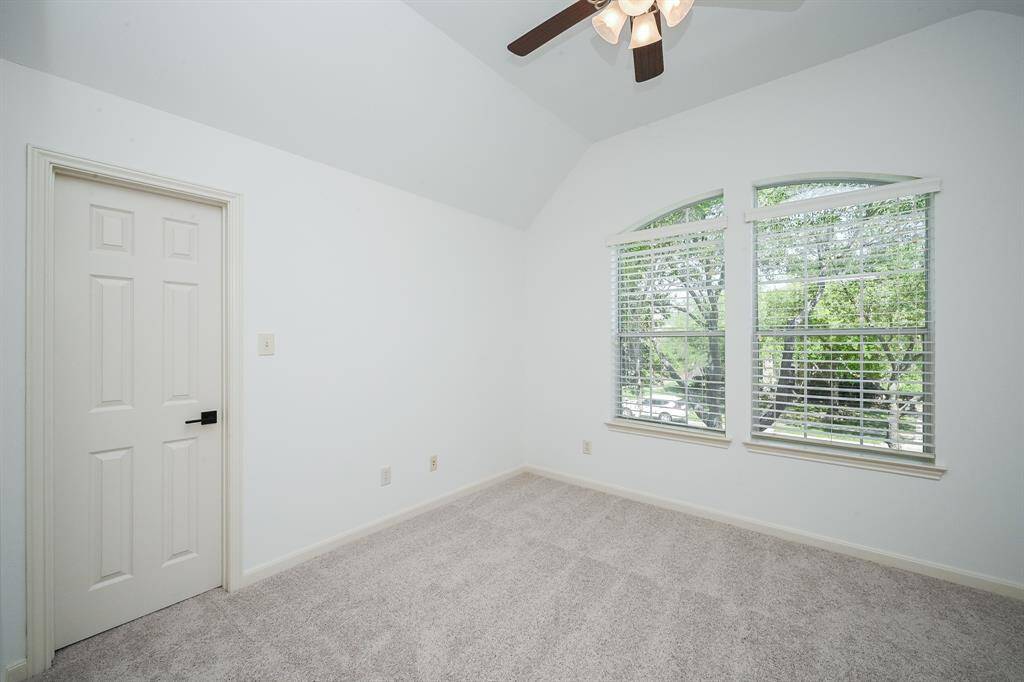Secondary bedroom features large windows and plush carpet.
