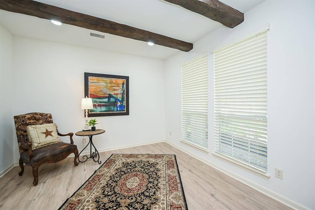The welcoming den features large windows, new flooring, fresh paint, beams on the ceiling, and recessed lighting.