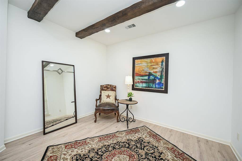 The welcoming den features large windows, new flooring, fresh paint, beams on the ceiling, and recessed lighting.