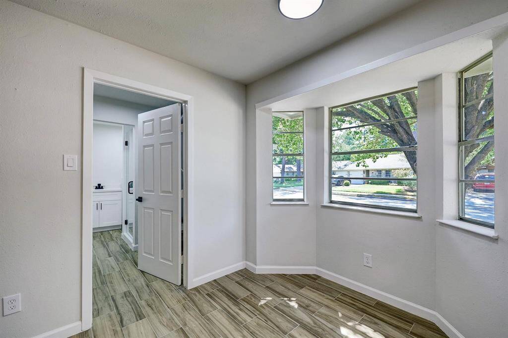 Nestled beside the kitchen, this cozy breakfast nook is filled with sunlight from surrounding windows. Just steps away is a convenient full bathroom, perfect for guests or quick access from the living areas.