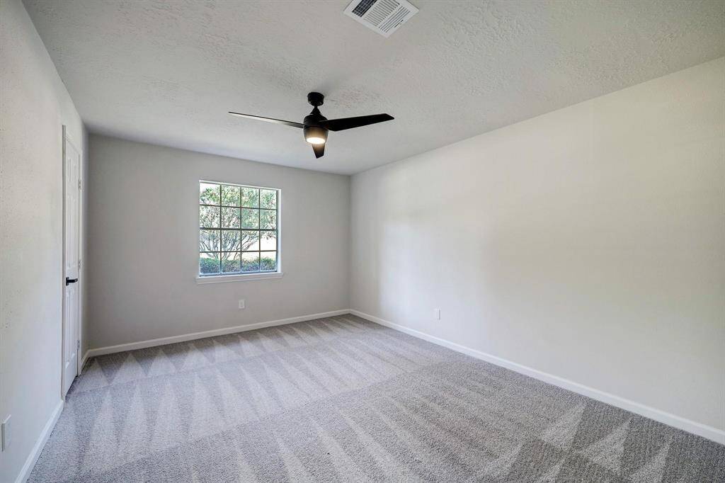 Equally spacious, this additional bedroom includes a large window, soft carpeting underfoot, and a ceiling fan. Ideal for guests, an office, or a creative space.