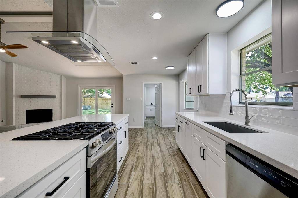 A standout culinary space, the kitchen features a clean, modern design with ample white cabinetry, quartz countertops, and a generously sized peninsula offering extra prep space and barstool seating. Lighting is thoughtfully layered with recessed and surface-mount fixtures.