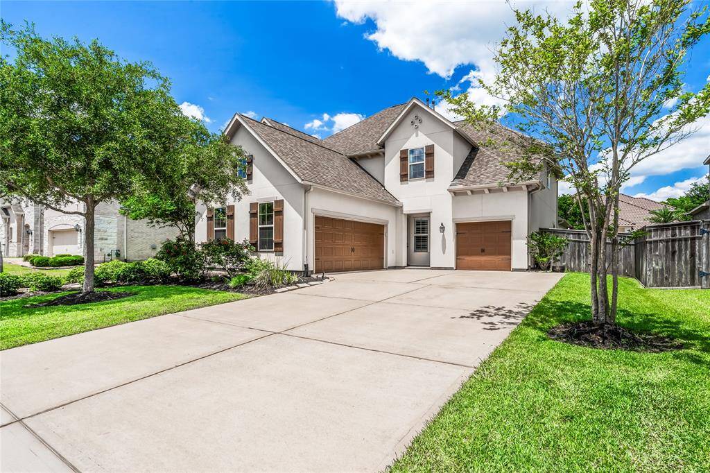 Charming home with a stone and stucco exterior, featuring a well-maintained front yard with lush greenery and mature trees. The inviting pathway leads to an arched wooden door, complemented by decorative shutters on the windows for a classic touch.