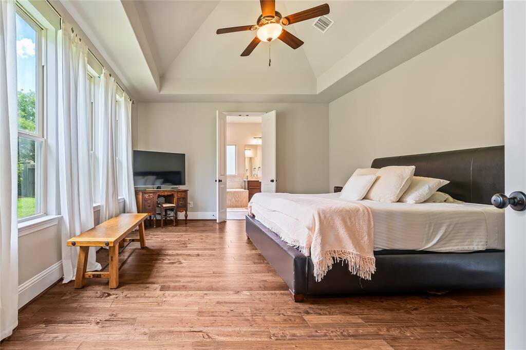 This spacious bathroom features dual vanities with granite countertops, a large soaking tub, and elegant lighting. The neutral tones and tiled flooring create a relaxing atmosphere, while the arched doorway adds a touch of sophistication.