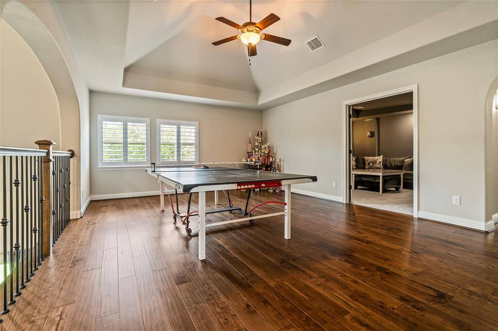 Cozy home theater room with plush carpeting, a large sectional sofa, and ambient wall lighting. Features a sleek, modern TV setup for an ideal entertainment experience.