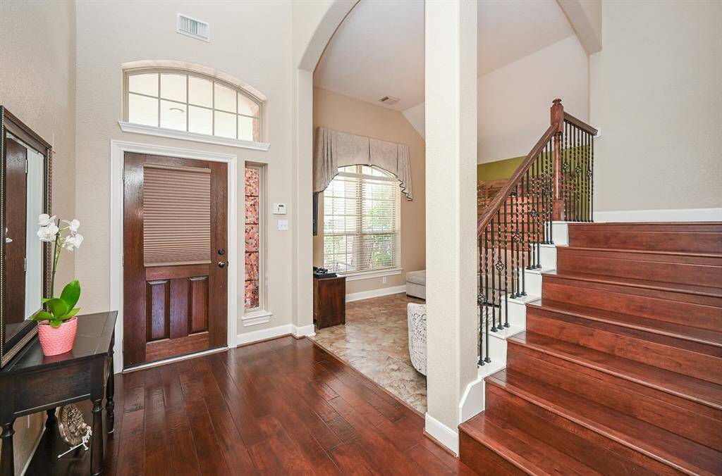 This is the stunning view of the front entrance from the inside; with soaring ceilings, cool, tranquil walls, tile and wood flooring, and dramatic staircase.