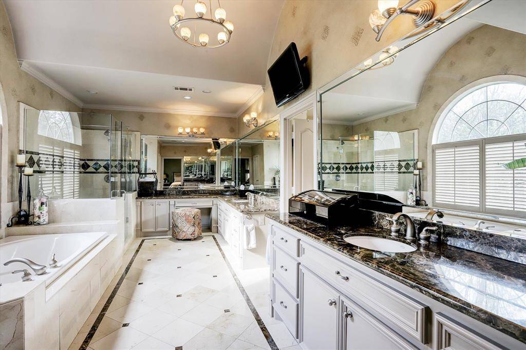 The primary bathroom offers two sinks, a vanity area, a soaking tub, and a walk-in shower.