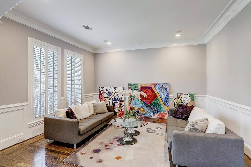 The formal living room has hardwood floors, crown molding, and windows overlooking the front of the home.