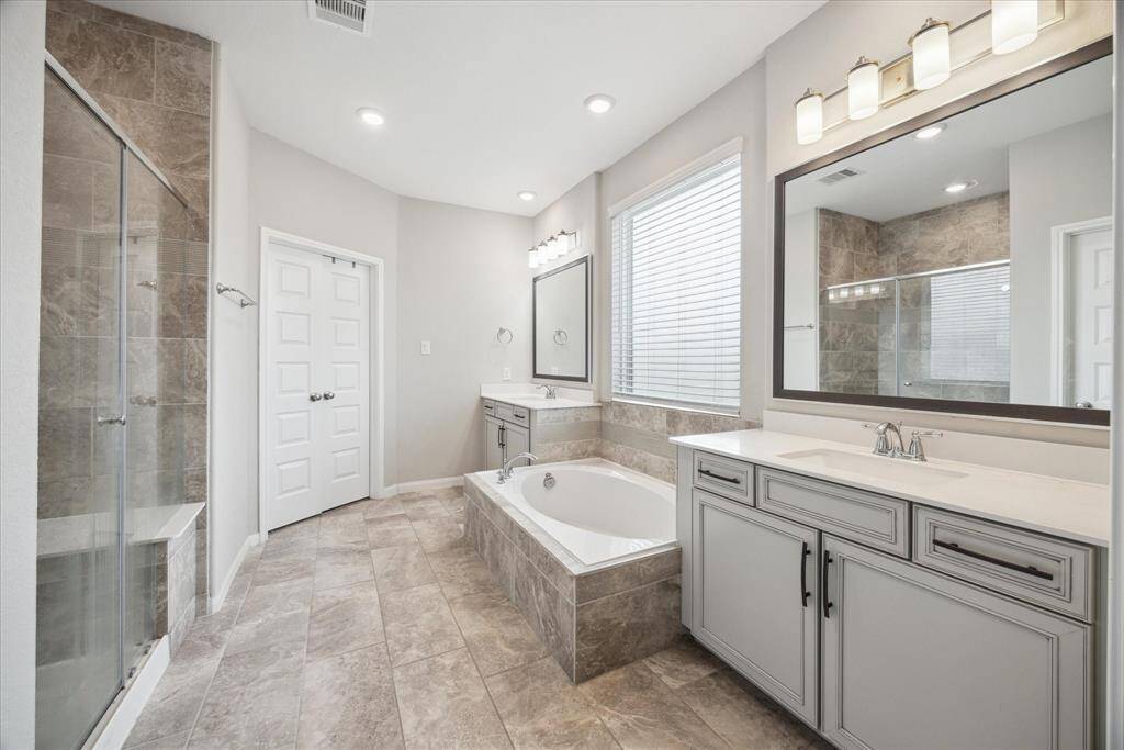 The beautiful primary bathroom features a relaxing soaking tub, a separate shower and dual vanities. A delightful retreat for unwinding, with ample space and elegant finishes throughout. Behind the double doors is the walk-in closet!