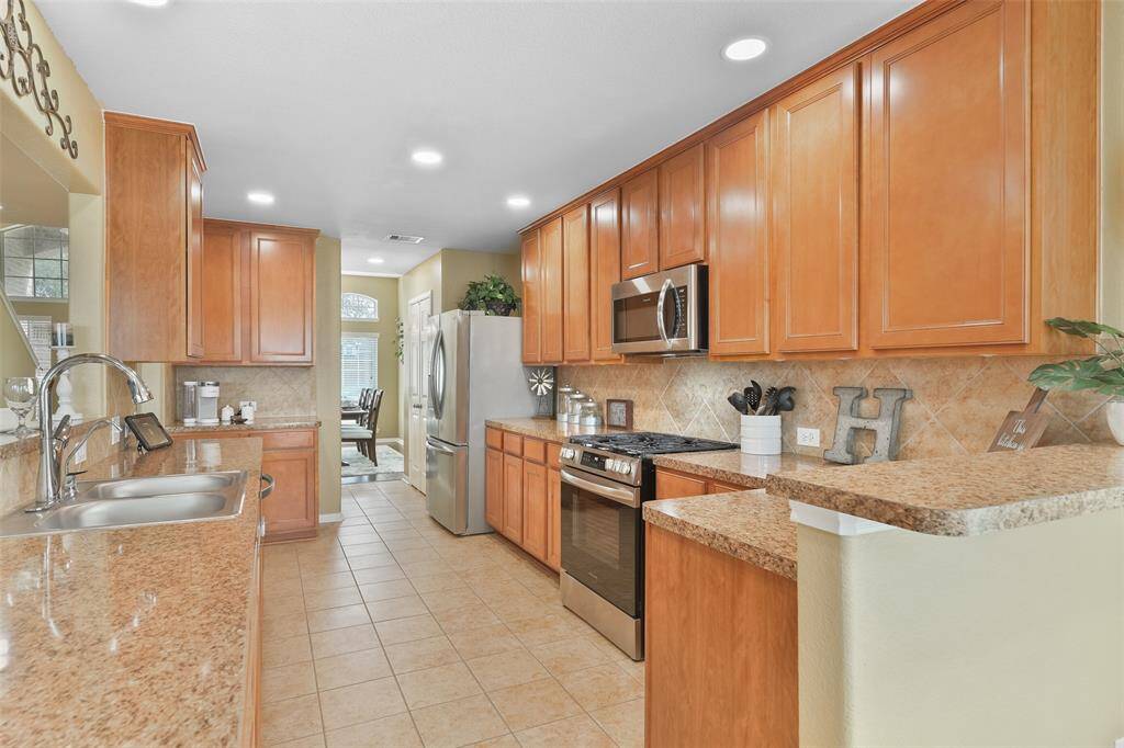 Adjoining the family room is that galley kitchen that opens directly into the dining room and breakfast room. Fine finishes in this space include Wilsonart high-definition granite-inspired laminate countertops, a tile backsplash, adjustable LED recessed lights, and ample 42-inch cabinetry.