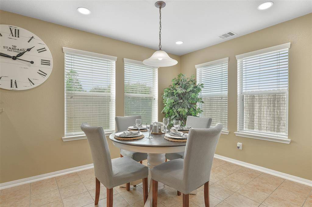 Tucked between the family room and the kitchen, there is a casual eat-in breakfast room anchored by a single pendant light above the table space. You'll enjoy easy maintenance tile floors and two walls of sunlit windows with 2-inch blinds.