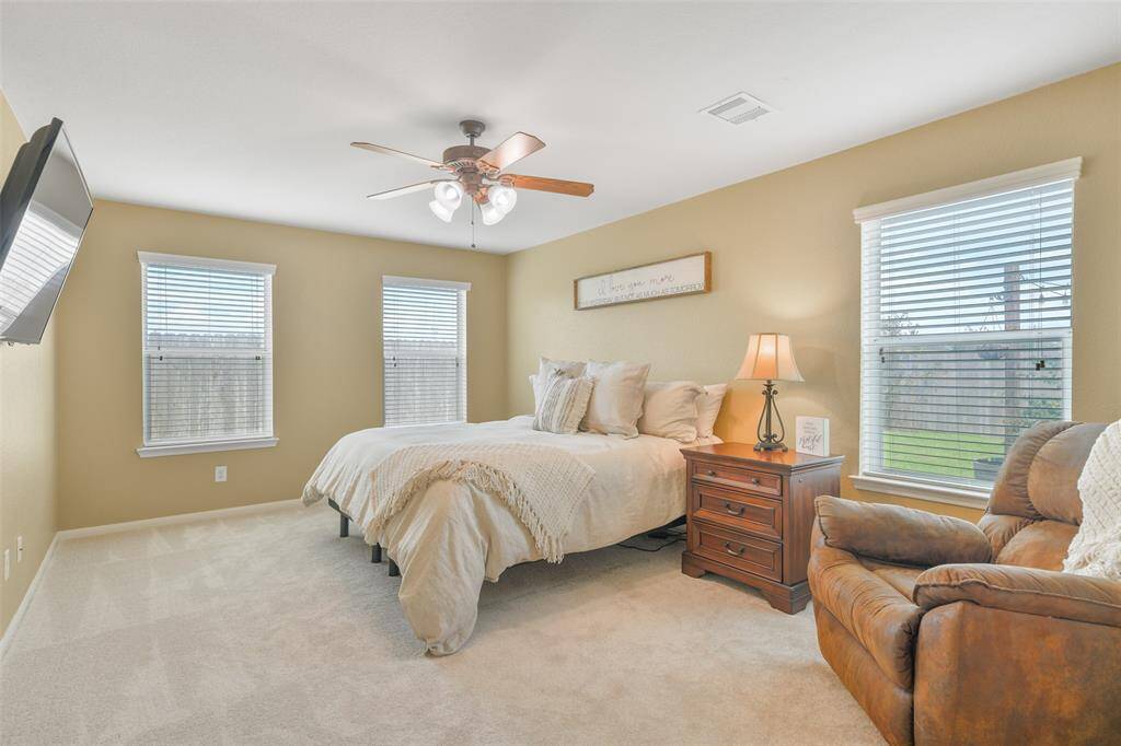 This spacious owners retreat is tucked just off of the family room and it features plush new carpet underfoot, a lighted ceiling fan, attractive neutral paint, and numerous windows with 2-inch blinds and views of the backyard and green space beyond.