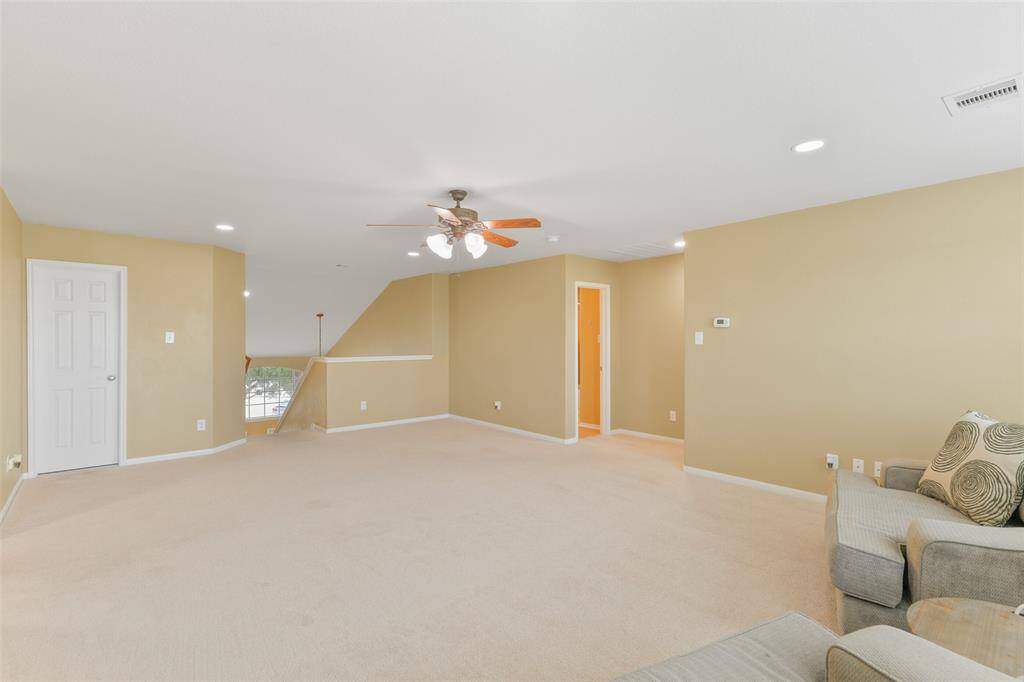 A carpeted staircase leads from the front foyer up to this large game room that's perfect for kids' toys, game nights, or movie dates! Note the plush new carpet, adjustable LED lighting, neutral paint, walk-in attic access, and windows with green space views.