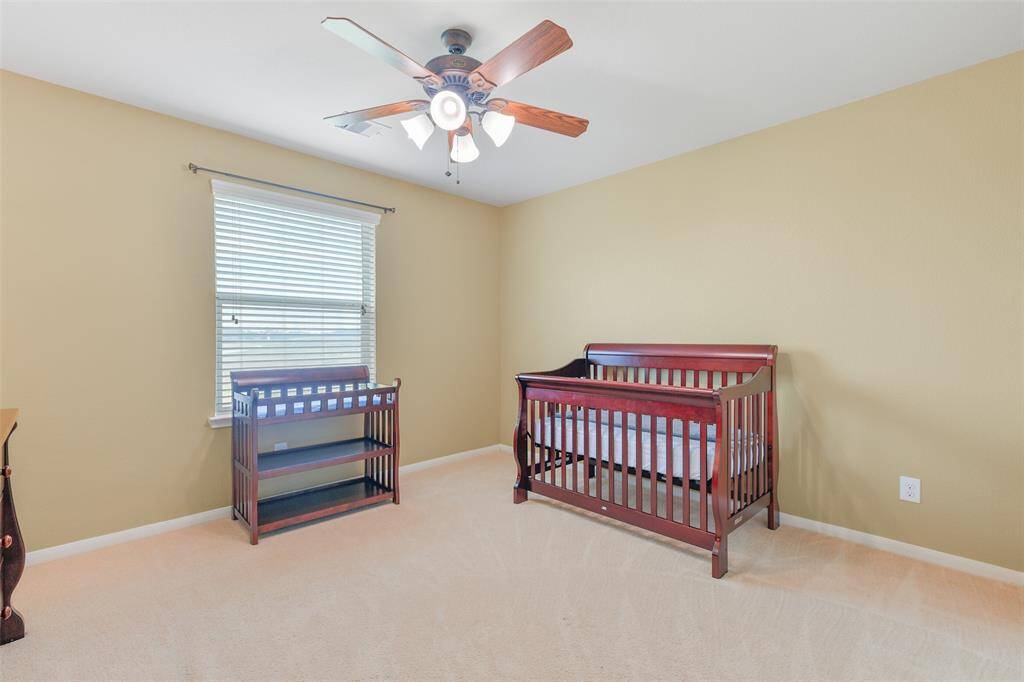 The first of three secondary bedrooms that are all located on the second floor offers a lighted ceiling fan, plush carpet, neutral paint, a sliding door closet, and a window with 2-inch blinds and views of the pond and green space behind the home.
