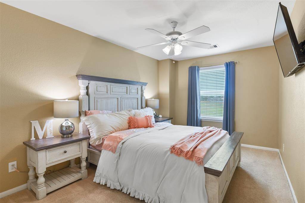 The fourth and final bedroom in the home is much like the others, also offering neutral paint, a lighted ceiling fan, plush carpet, a large walk-in closet, a sunlit window with green space views, and a full bathroom just outside the door.