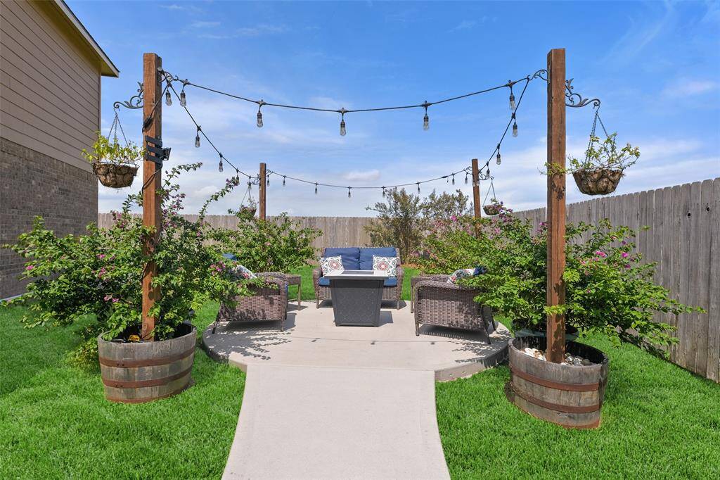 This adorable concrete patio area is accessible from a sidewalk that leads through a privacy gate to the double-wide driveway in the front yard. It comes complete with string lights - just add your own plants and firepit to recreate this inviting space!