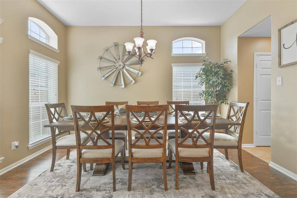 A wide entrance leads from the foyer into this extra spacious formal dining room with a raised ceiling, a 5-light chandelier, luxury laminate plank floors, numerous windows, and convenient access directly into the kitchen.