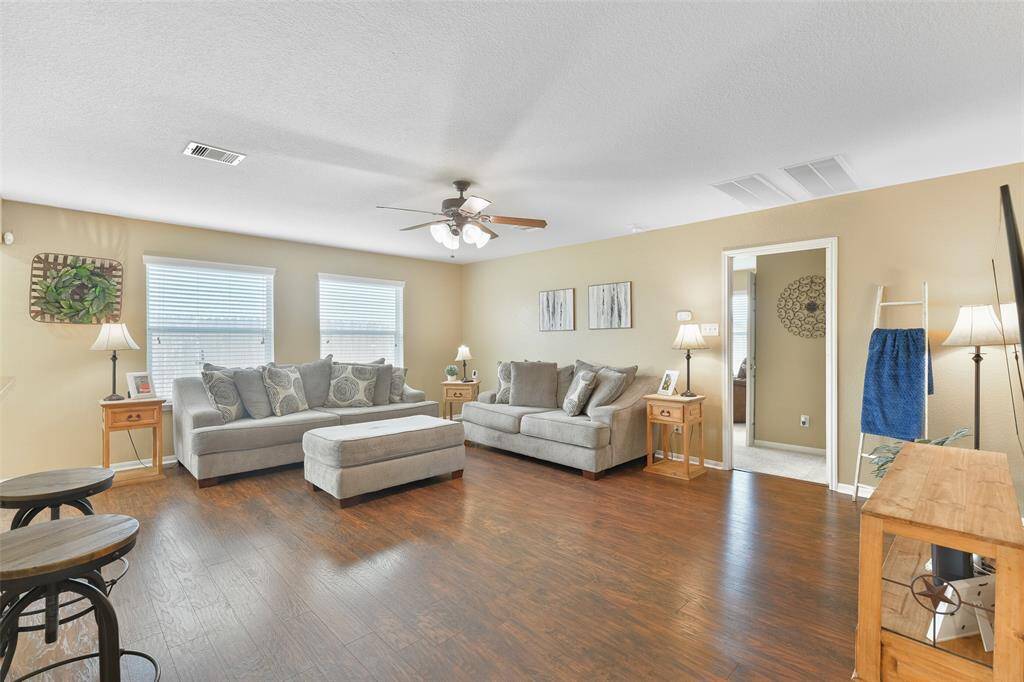 Looking in the opposite direction in the family room, notice the wall of rear-facing windows shaded by 2-inch blinds, the ample space to spread out and entertain, and a peek around the corner into the master suite.