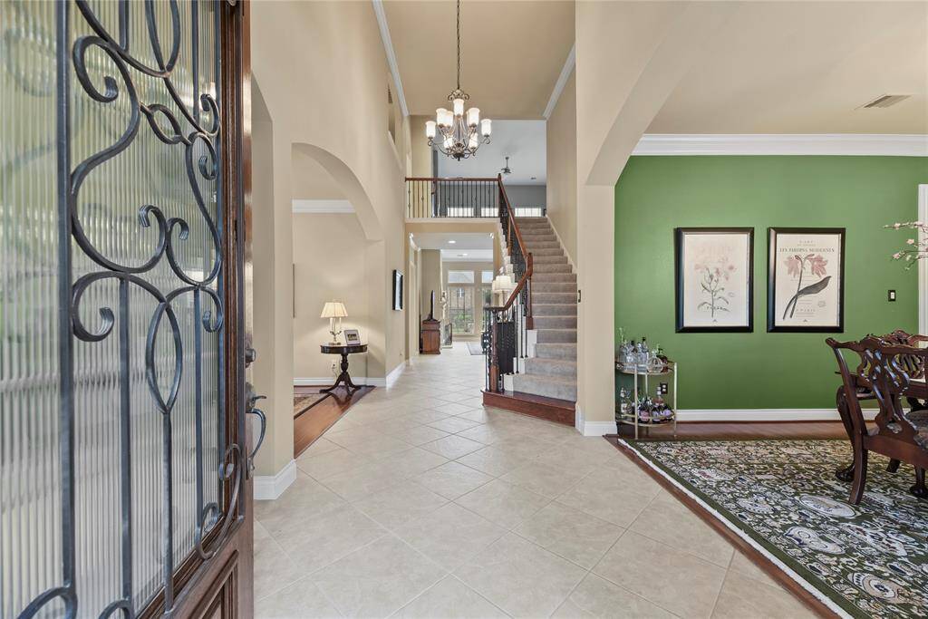 Foyer with diamond tile pattern, winder staircase with wooden landing, and high ceilings that lead toward the heart of the home create an expansive and inviting area for you to greet your guests.