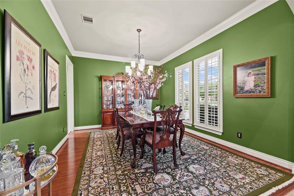 Formal Dining Room with polished wooden floor, crown molding, and wooden shutters create an ideal atmosphere for luxurious dinners and relaxed family gatherings.