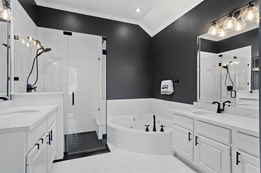The primary bathroom features tile floors, dual sinks, walk-in shower, and jetted tub.
