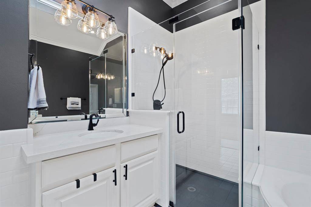 The walk-in shower has tile surround and a glass door.