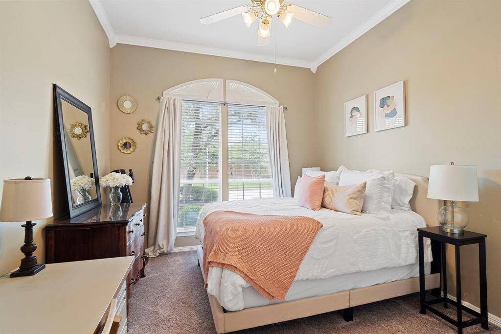 Secondary bedroom features largewindows, custom paint, crown molding, and plush carpet.