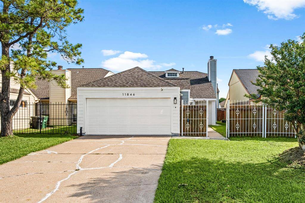 Charming two-story curb appeal with a white iron fence, wood accents, and detached garage.