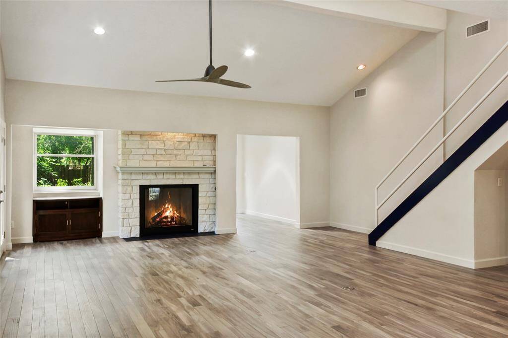This spacious kitchen features modern stainless steel appliances, elegant white cabinetry, and a striking blue tile backsplash. It has ample counter space and natural light, creating a bright and inviting atmosphere.