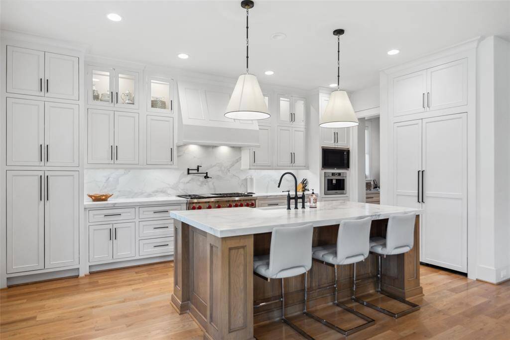 Chef's Kitchen offers a large island 2/ quartz counters, cabinets to the ceiling w/ glass fronts, pot/pan drawers, pot filler, Panel-front Refrigerator, 48" Wolf Range, Bosch Coffee Maker & Designer pendant lighting.