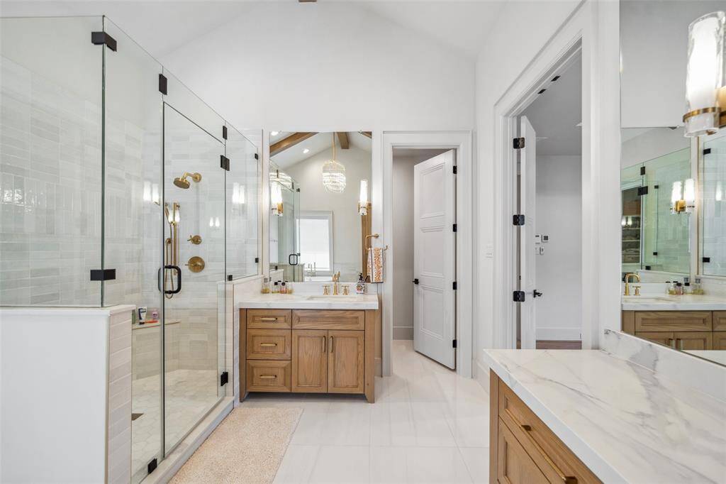 Glass-encased shower w/ golden fixtures, unique lighting fixtures built-into mirror, high-end cabinet hardware and more.
