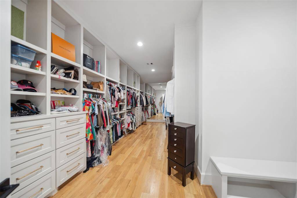 Primary Walk-in closet offers wall to wall custom wardrobe built-ins w/ 2 full size mirrors, bench & direct access to Laundry Room which offers 2 sets of Washer & Dryer included in the Home.