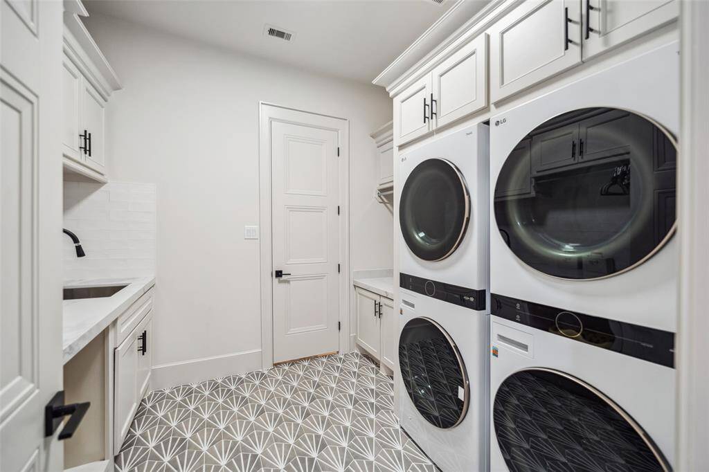 Laundry room features 2 sets of washers and dryers, full sink and space to hang clothes.