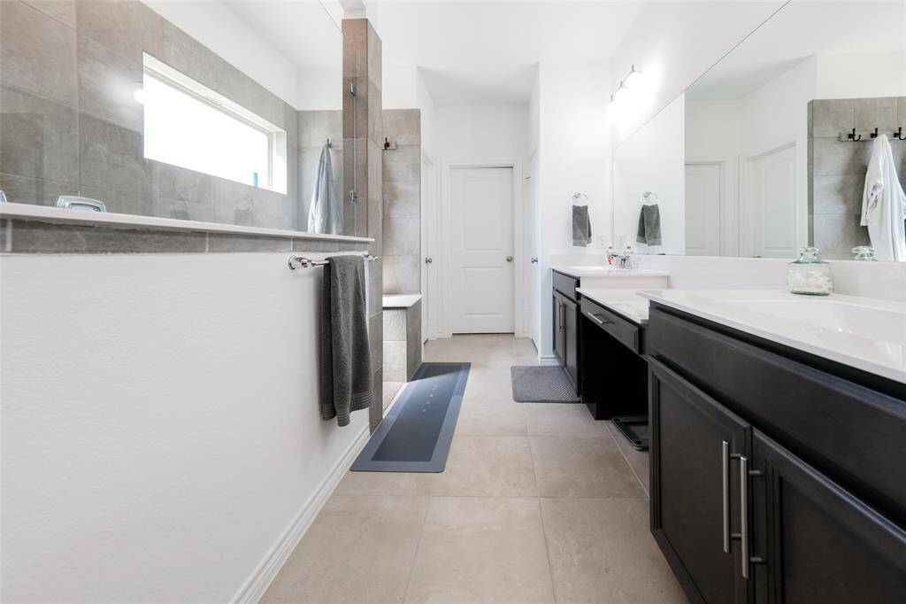 Spacious primary bath leads to 'her' closet, while 'his' closet is conveniently set off in the primary bedroom for ultimate privacy and organization.