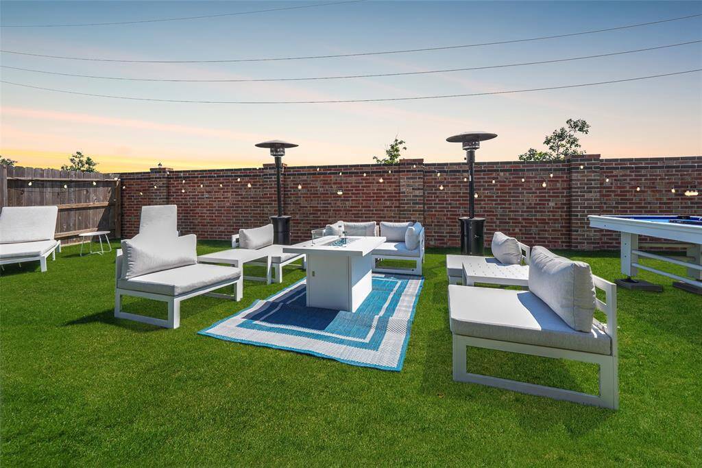 This turf-covered backyard has it all—ample space for outdoor seating, a pool table, and a designated picnic area for endless fun.
