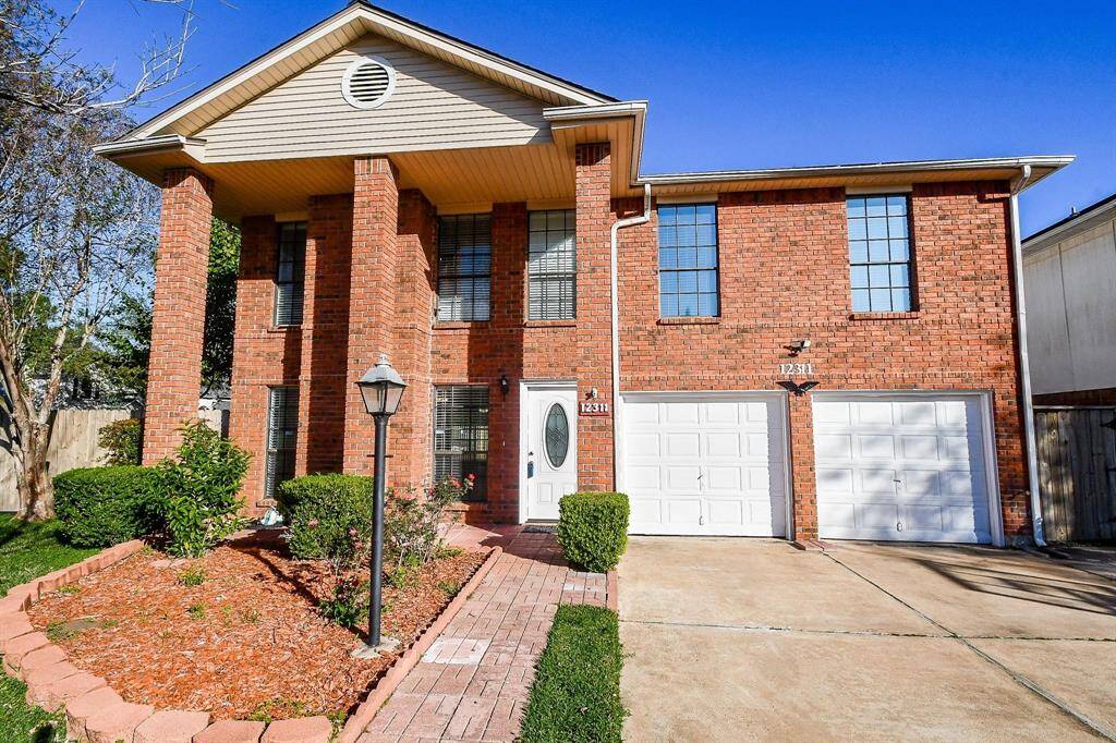 Two story red brick home with double wide driveway