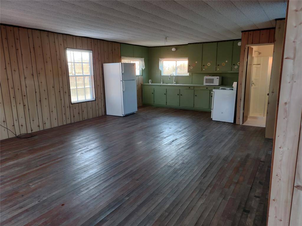 View from front entry. One room cabin, kitchen on back wall.