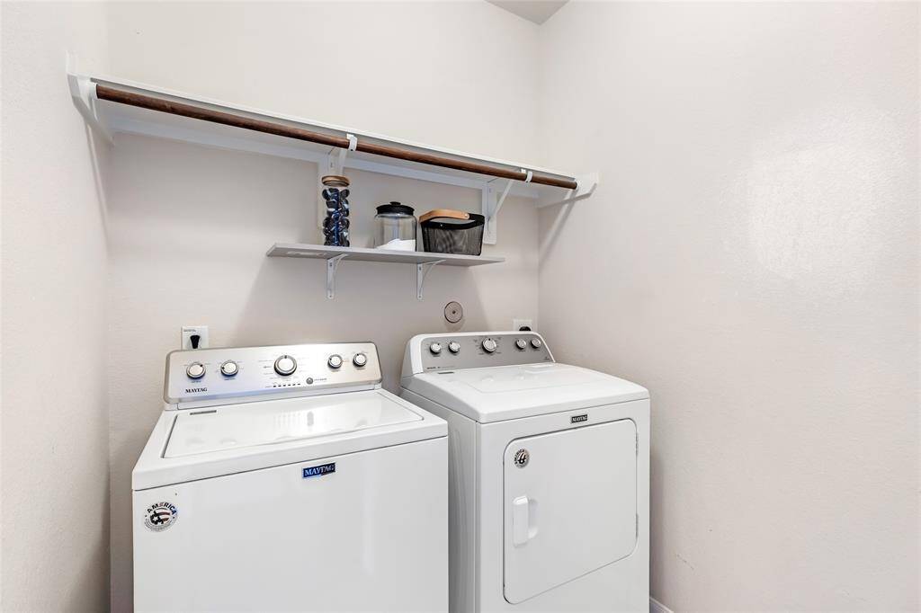 Compact laundry room with a shelf above for storage and organization. The space is clean and functional.