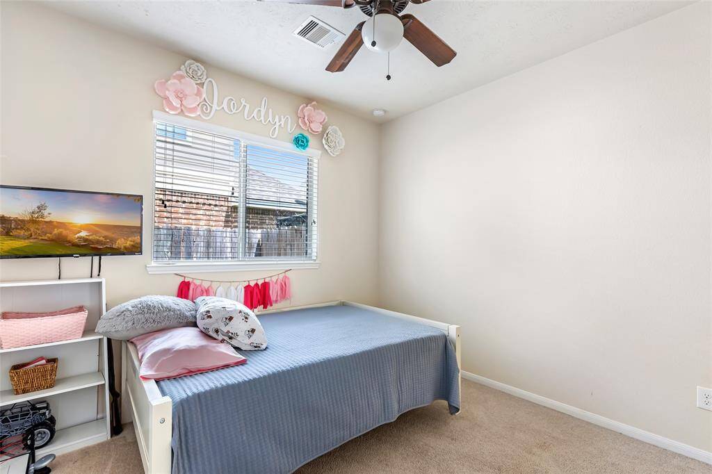 This cute as can be and cozy bedroom features a large window providing natural light, complementing the soft, neutral paint and carpeted floor. Perfect for a child's room or guest space.