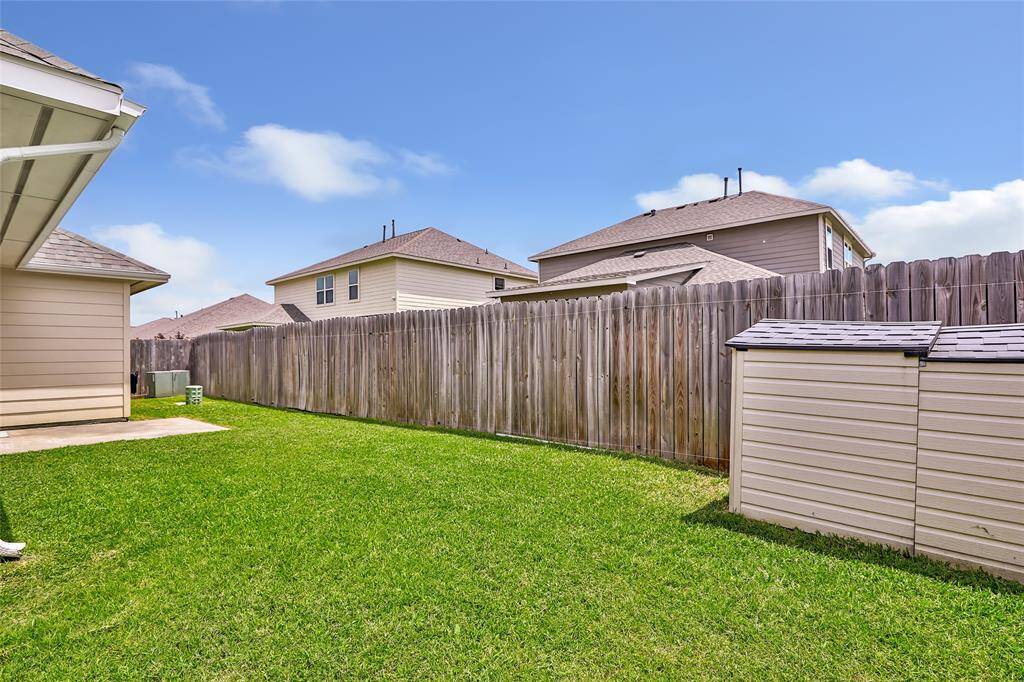 Well-maintained backyard with a neatly trimmed lawn, wooden privacy fence, and a small storage shed, ideal for outdoor activities and storage.